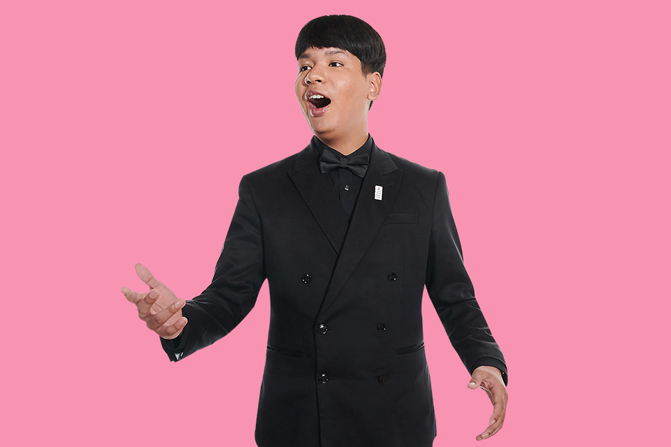 A singer dressed in black on a pink background